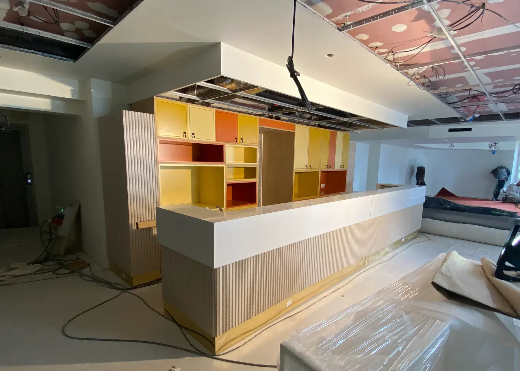 Création d'une banque d'accueil beige, orange et jaune avec plusieurs étagères de rangement