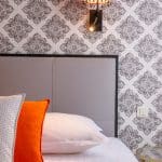Image d'une tête de lit grise en dessous d'une lampe orange